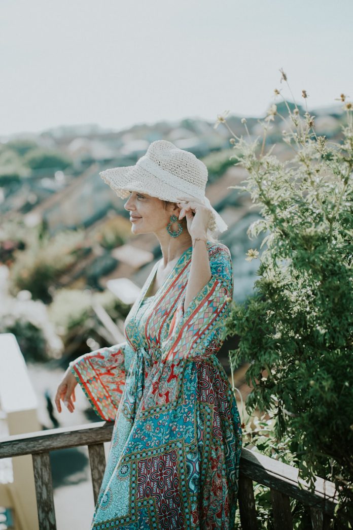 Woman in a colorful dress and hat on a balcony