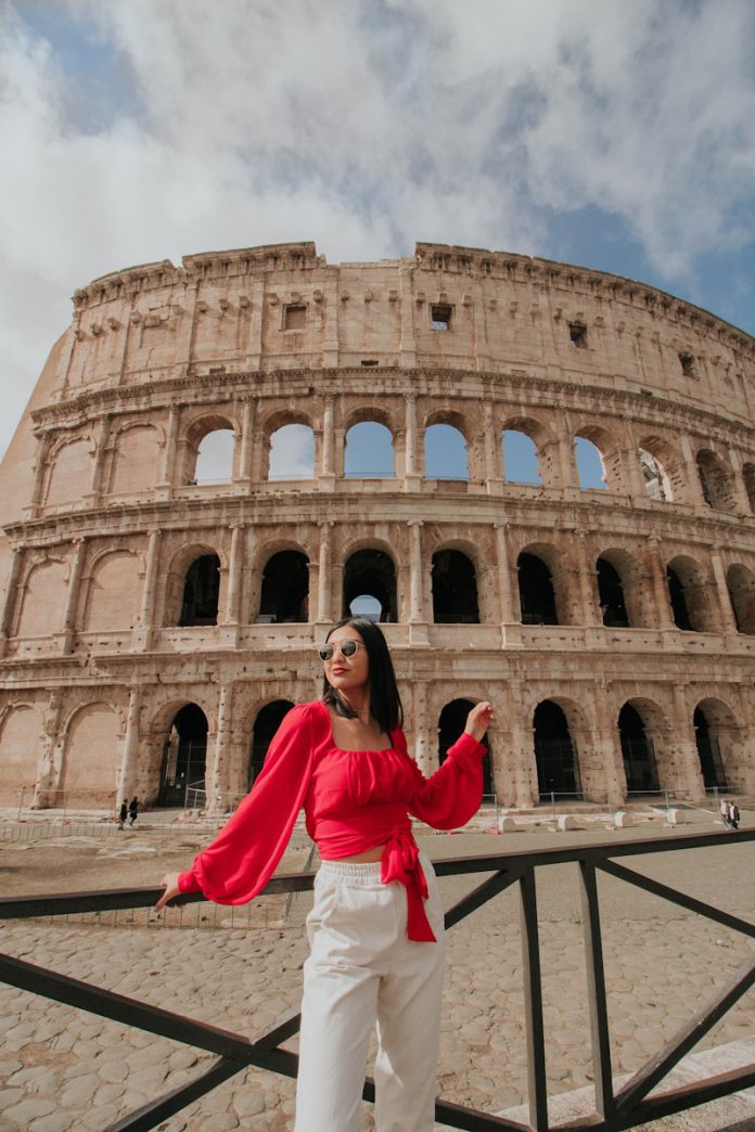 woman in white long sleeve shirt and pink pants standing near brown concrete building during daytime